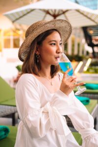 a woman in a hat drinking a glass of wine