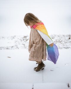a little girl walking in the snow with a kite