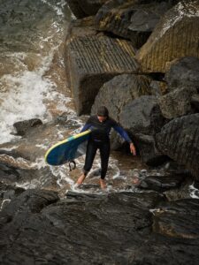 a person in a wet suit carrying a surfboard