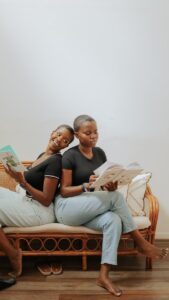 a woman and a man sitting on a couch and reading a book
