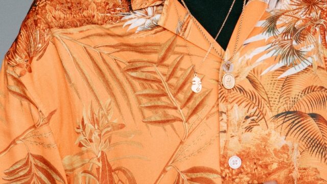 a man wearing an orange hawaiian shirt with palm leaves on it