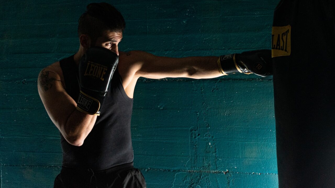 man in black tank top and black shorts wearing black boxing gloves