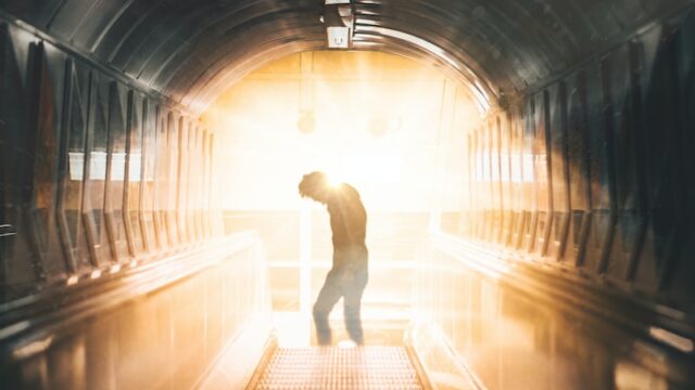 a man is walking down an escalator in a tunnel